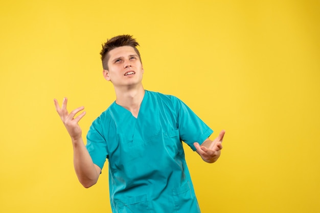 Vista frontal joven médico en traje médico sobre fondo amarillo