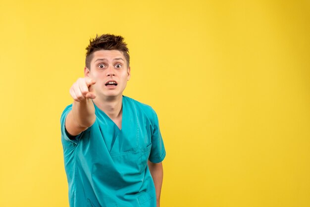 Vista frontal joven médico en traje médico sobre fondo amarillo