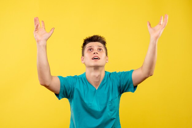 Vista frontal joven médico en traje médico sobre fondo amarillo