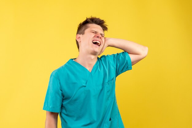 Vista frontal joven médico en traje médico sobre fondo amarillo