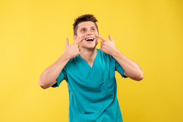 Vista frontal joven médico en traje médico sobre fondo amarillo