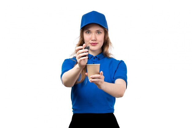 Una vista frontal joven mensajero en camisa azul gorra azul y pantalón negro con taza de café sobre blanco