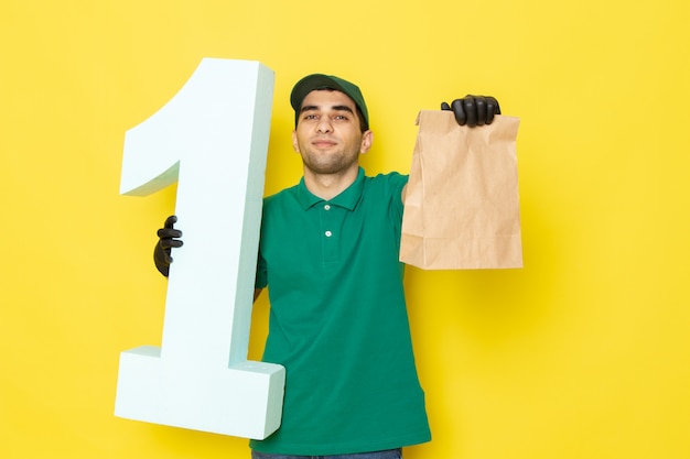 Foto gratuita vista frontal joven mensajero en camisa verde gorra verde guantes negros con paquete y número uno en amarillo