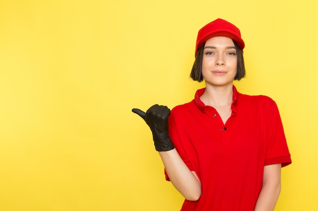 Una vista frontal joven mensajero femenino en rojo uniforme guantes negros y gorra roja posando