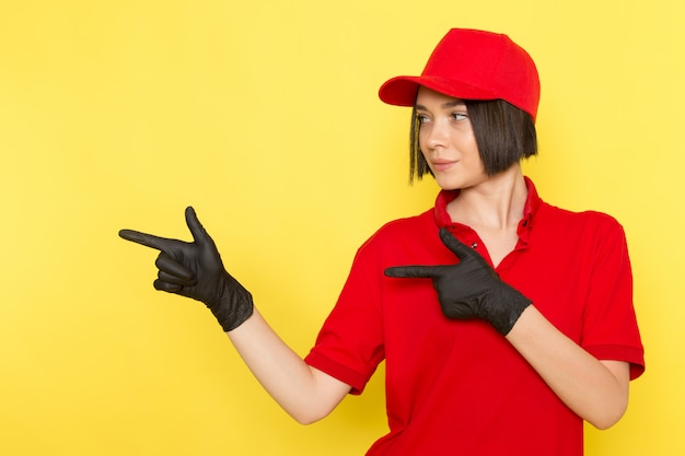 Una vista frontal joven mensajero femenino en rojo uniforme guantes negros y gorra roja posando