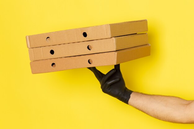 Vista frontal joven mensajero sosteniendo cajas de entrega en amarillo