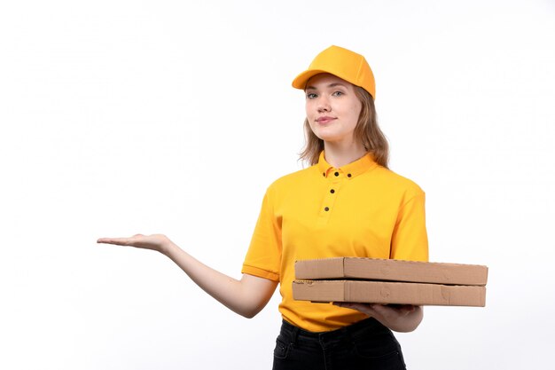 Una vista frontal joven mensajero trabajadora del servicio de entrega de alimentos con cajas de pizza con una sonrisa en su rostro en blanco