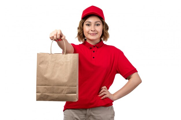 Una vista frontal joven mensajero trabajadora del servicio de entrega de alimentos con paquete de entrega de alimentos sonriendo en blanco