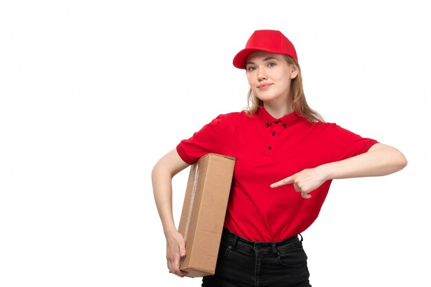 Una vista frontal joven mensajero trabajadora del servicio de entrega de alimentos sonriendo sosteniendo una enorme caja de entrega en blanco