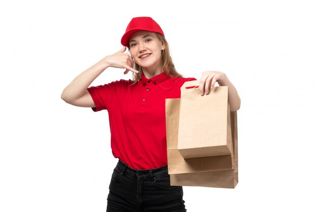 Una vista frontal joven mensajero trabajadora del servicio de entrega de alimentos sonriendo sosteniendo paquetes de entrega en blanco