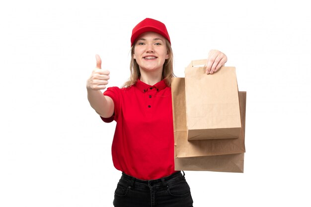 Una vista frontal joven mensajero trabajadora del servicio de entrega de alimentos sonriendo sosteniendo paquetes de entrega en blanco