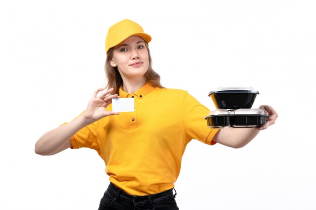 Una vista frontal joven mensajero trabajadora del servicio de entrega de alimentos con tazones de comida tarjeta blanca y sonriente en blanco