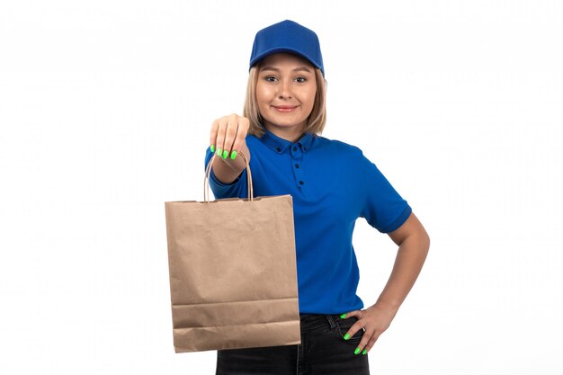 Una vista frontal joven mensajero en uniforme azul con paquete de entrega de alimentos