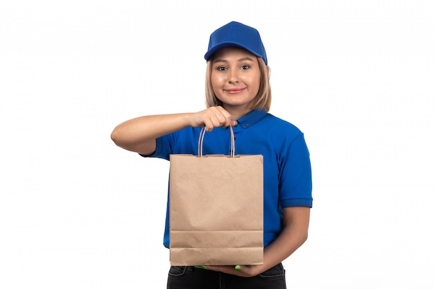 Una vista frontal joven mensajero en uniforme azul con paquete de entrega de alimentos