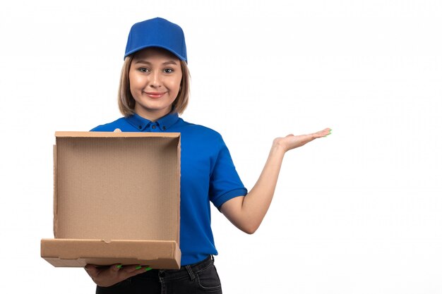 Una vista frontal joven mensajero en uniforme azul con paquete de entrega de alimentos