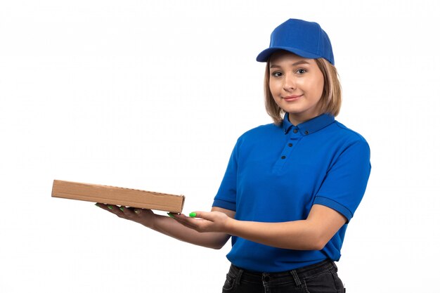 Una vista frontal joven mensajero en uniforme azul con paquete de entrega de alimentos