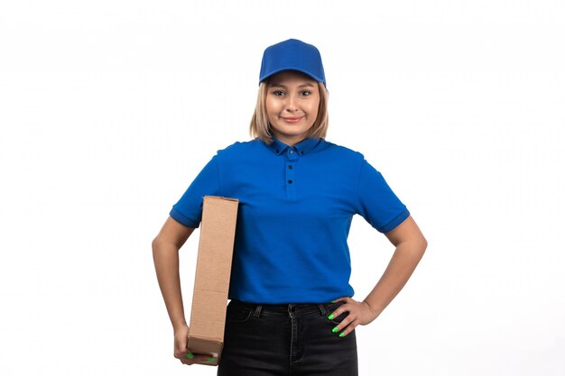 Una vista frontal joven mensajero en uniforme azul sosteniendo el paquete de entrega de alimentos con una sonrisa en su rostro