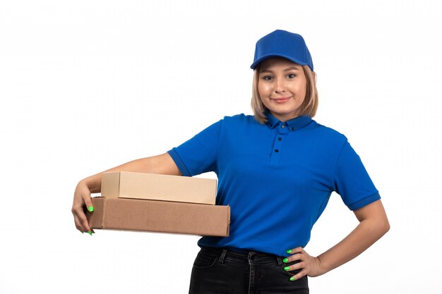 Una vista frontal joven mensajero en uniforme azul sosteniendo el paquete de entrega de alimentos con una sonrisa en su rostro