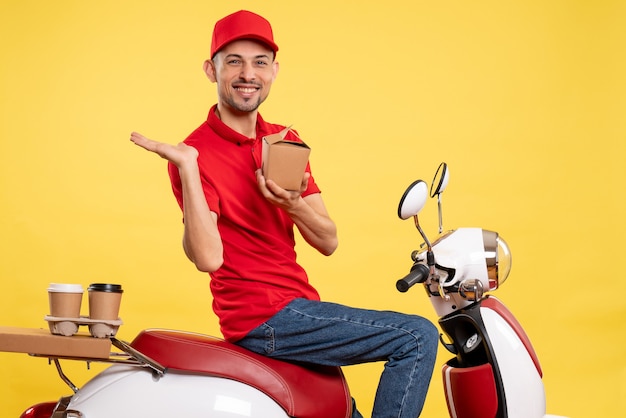 Foto gratuita vista frontal joven mensajero en uniforme rojo con comida de entrega sobre fondo amarillo