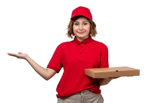 Una vista frontal joven mensajero en uniforme sosteniendo el paquete de entrega sonriendo