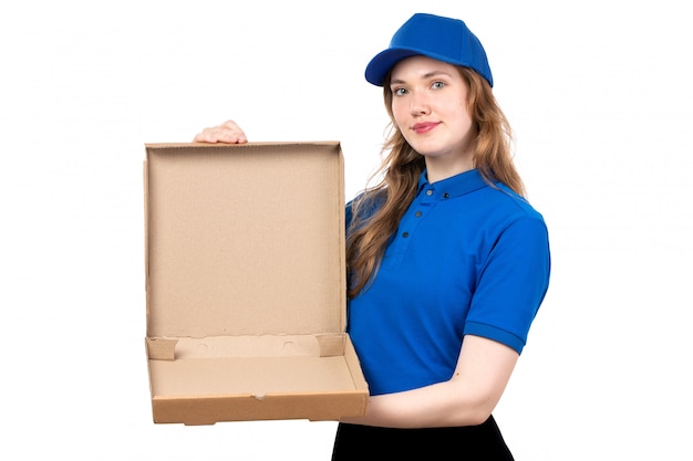 Una vista frontal joven mensajero en uniforme sosteniendo un paquete de entrega vacío sonriendo