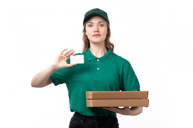 Una vista frontal joven mensajero en uniforme verde con cajas con pizza y tarjeta blanca sobre blanco