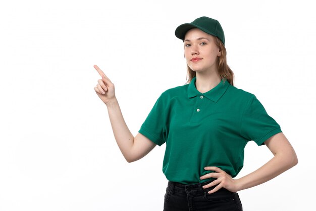 Una vista frontal joven mensajero en uniforme verde sonriendo posando con el dedo levantado