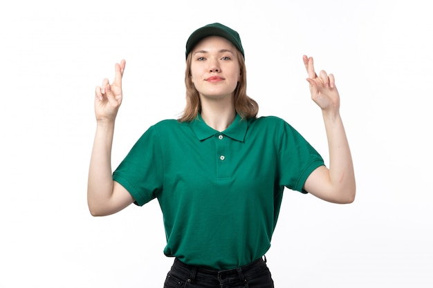 Una vista frontal joven mensajero en uniforme verde sonriendo posando con los dedos cruzados