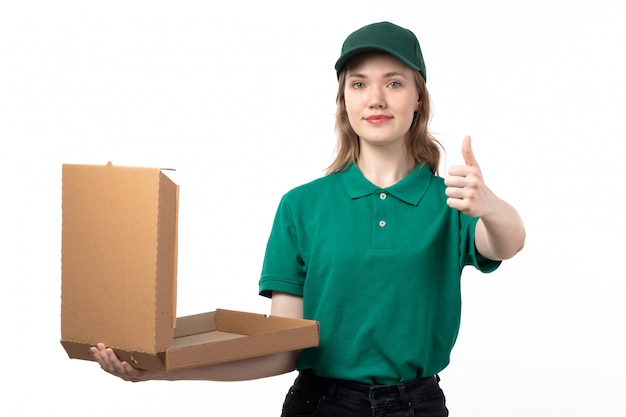 Una vista frontal joven mensajero en uniforme verde sonriendo sosteniendo una caja de pizza vacía