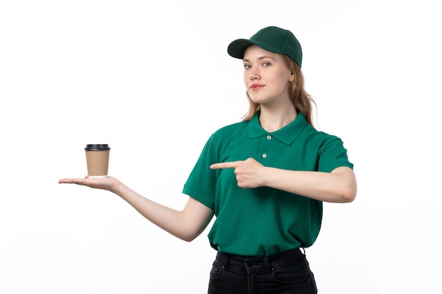 Una vista frontal joven mensajero en uniforme verde sonriendo sosteniendo la taza de café