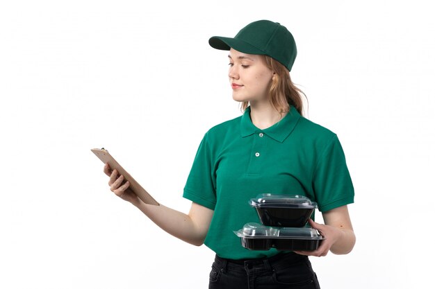 Una vista frontal joven mensajero en uniforme verde sosteniendo el bloc de notas para firmas y tazones con comida sonriendo