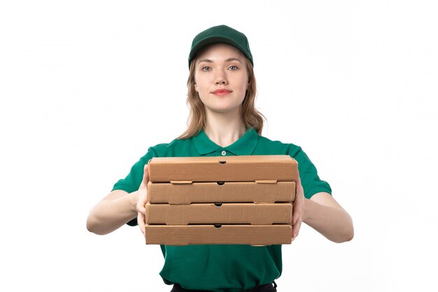 Una vista frontal joven mensajero en uniforme verde sosteniendo cajas de entrega de pizza sonriendo