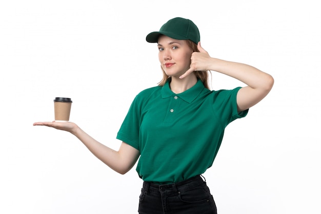Una vista frontal joven mensajero en uniforme verde con taza de café en blanco