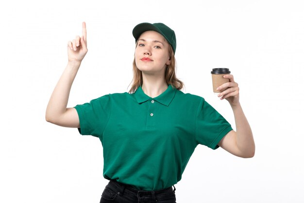 Una vista frontal joven mensajero en uniforme verde con taza de café en blanco