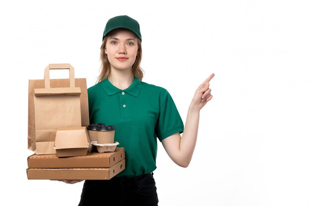 Una vista frontal joven mensajero en uniforme verde con tazas de café y paquetes de entrega de alimentos en blanco