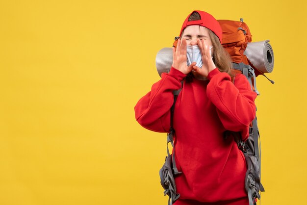 Vista frontal joven con mochila turística y máscara gritando