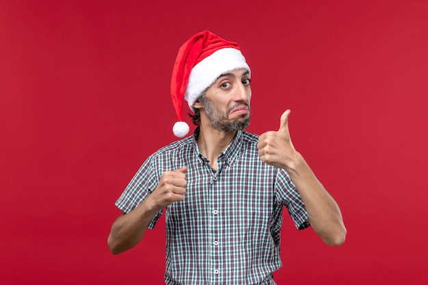 Vista frontal joven mostrando el número en la pared roja vacaciones año nuevo rojo masculino