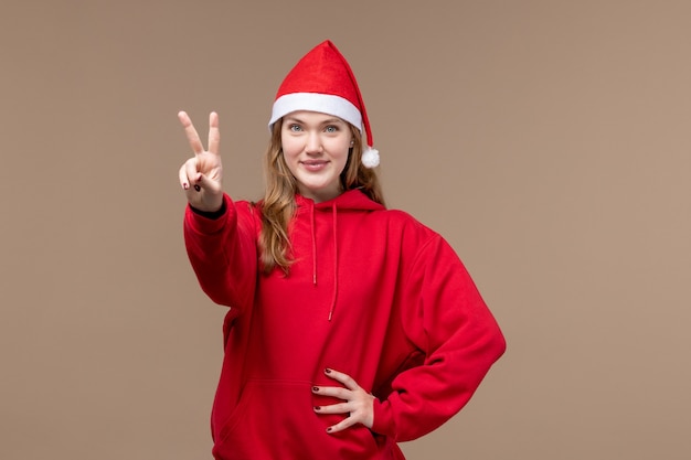 Vista frontal joven mostrando número sobre fondo marrón emoción vacaciones de Navidad