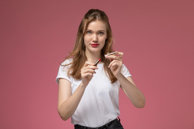 Vista frontal joven mujer atractiva en camiseta blanca con lápiz labial en la pared de color rosa oscuro modelo color mujer joven