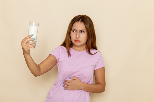 Vista frontal joven mujer atractiva en camiseta rosa y jeans con dolor de estómago debido a la leche ¡¡