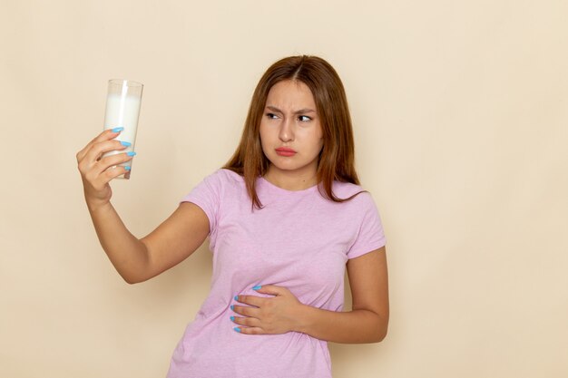 Vista frontal joven mujer atractiva en camiseta rosa y jeans con dolor de estómago debido a la leche ¡¡