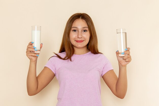 Vista frontal joven mujer atractiva en camiseta rosa y jeans con leche y agua