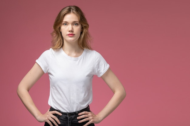 Vista frontal joven mujer atractiva posando en camiseta blanca en la pared rosa modelo color mujer joven