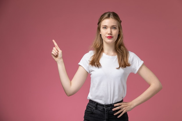 Vista frontal joven mujer atractiva simplemente posando en camiseta blanca en la pared rosa modelo color mujer joven