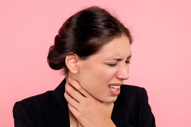 Vista frontal joven mujer bonita con dolor de garganta sobre fondo rosa