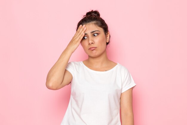 Una vista frontal joven mujer en camiseta blanca y jeans azul posando con expresión confusa