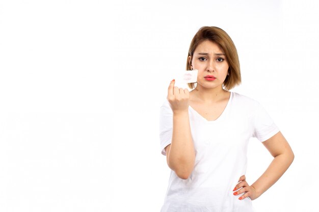 Una vista frontal joven mujer en camiseta blanca con vendaje blanco alrededor de su boca despegando en el blanco