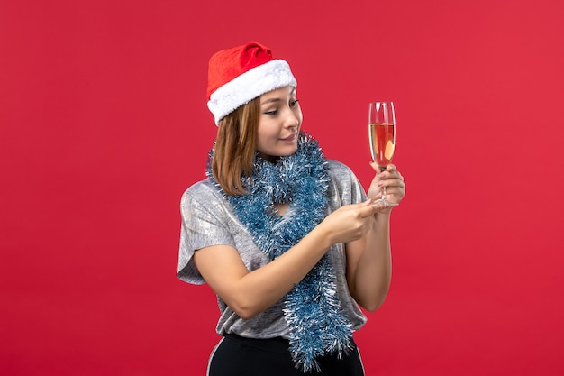 Vista frontal joven mujer celebrando el año nuevo en la pared roja fiesta de navidad