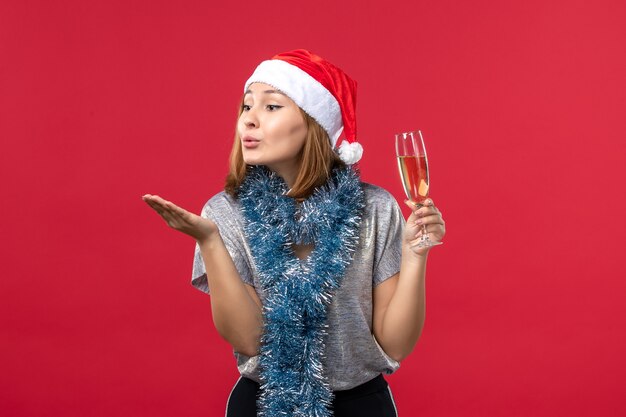 Vista frontal joven mujer enviando besos al aire en la pared roja fiesta navideña