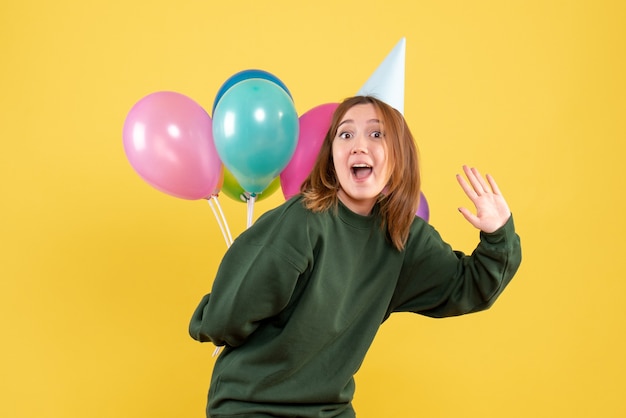 Vista frontal joven mujer escondiendo globos de colores